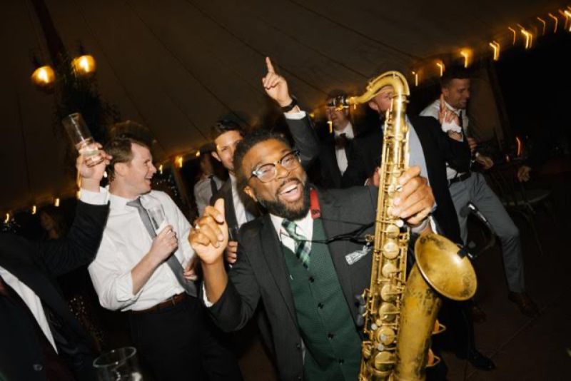 Dennison Blackett playing saxophone on a packed wedding dance floor